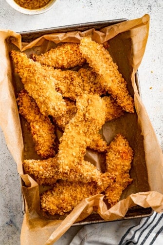 Air fryer chicken tenders in a paper-lined container.