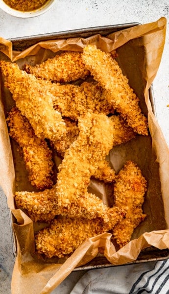 Air fryer chicken tenders in a paper-lined container.