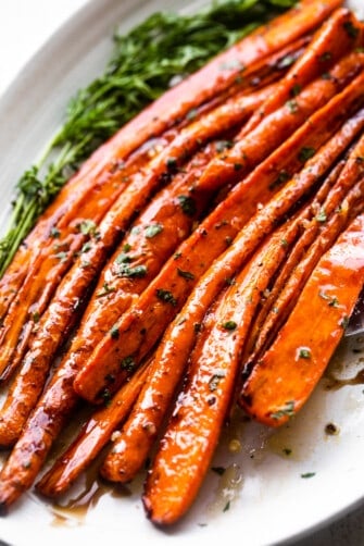 close up shot of air fryer cooked carrots arranged on a long oval platter and drizzled with balsamic glaze.