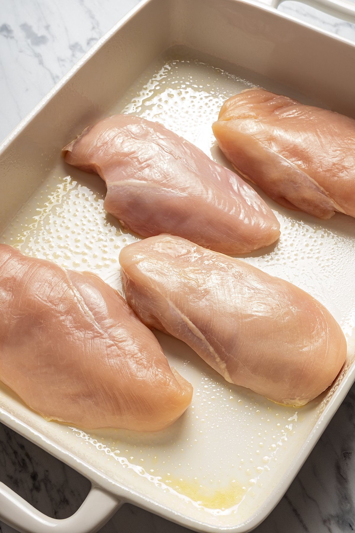 Uncooked chicken breasts in baking dish