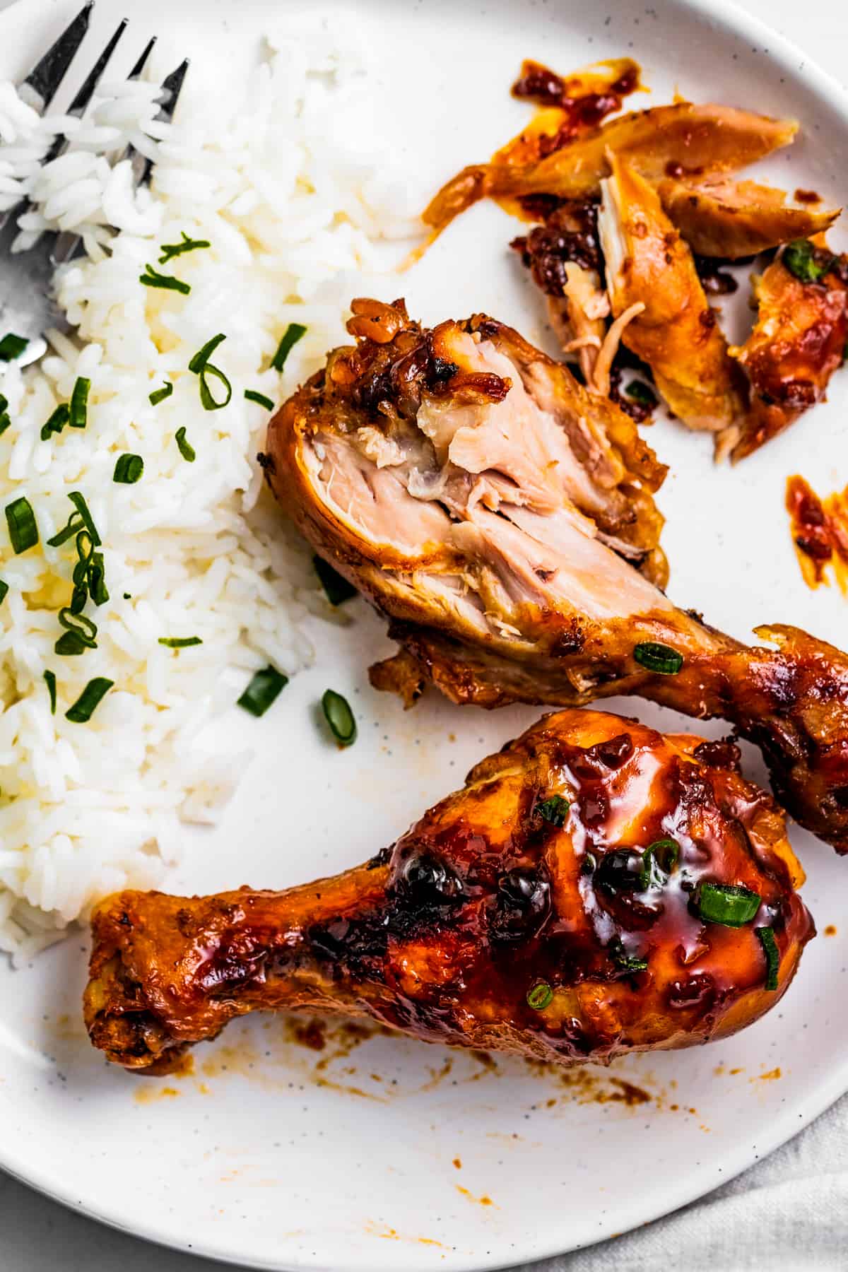 Chicken drumsticks on a plate with white rice.