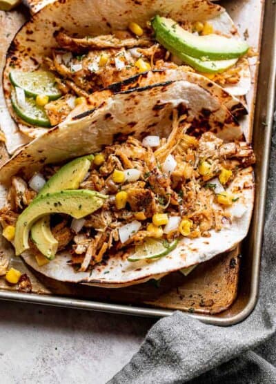 chicken carnitas tacos topped with avocado, onions, and corn