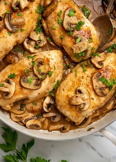 Top view of chicken marsala in a large skillet, topped with mushrooms and marsala wine sauce.