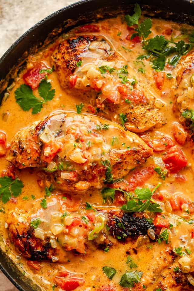 top shot of 3 chicken breasts in a skillet with coconut milk sauce