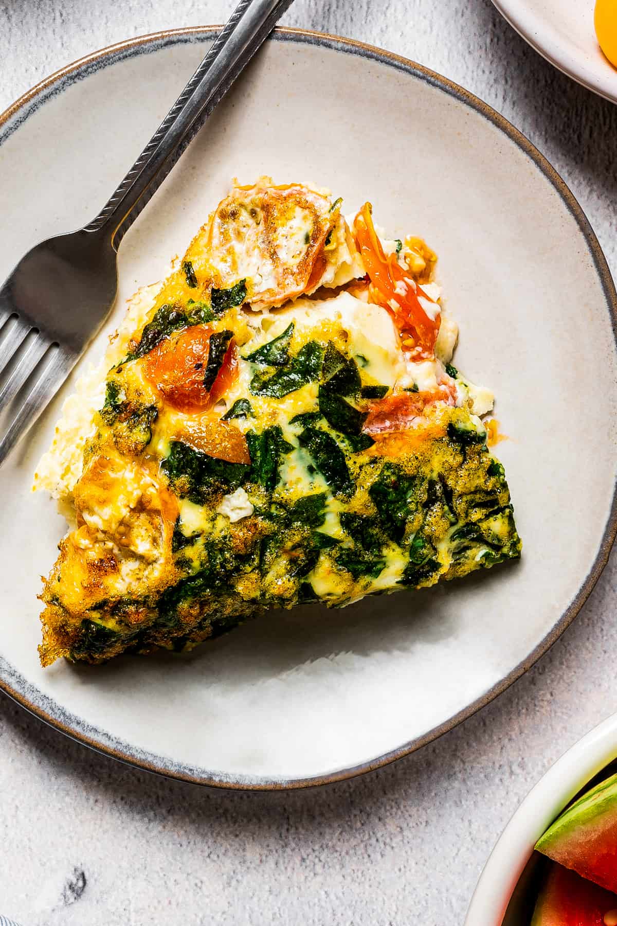A slice of egg white frittata on a plate with a fork.