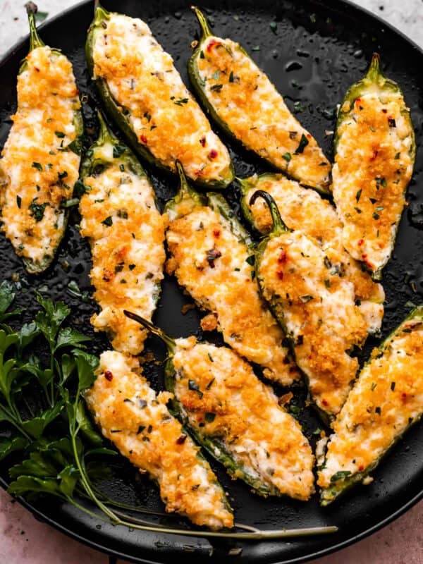 Air Fryer Jalapeno Poppers arranged on a round black plate and garnished with parsley.