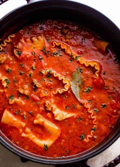overhead shot of a dark dutch oven filled with lasagna noodles in tomato broth