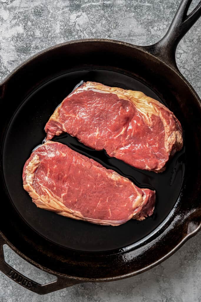 Searing ribeye steaks in a skillet.