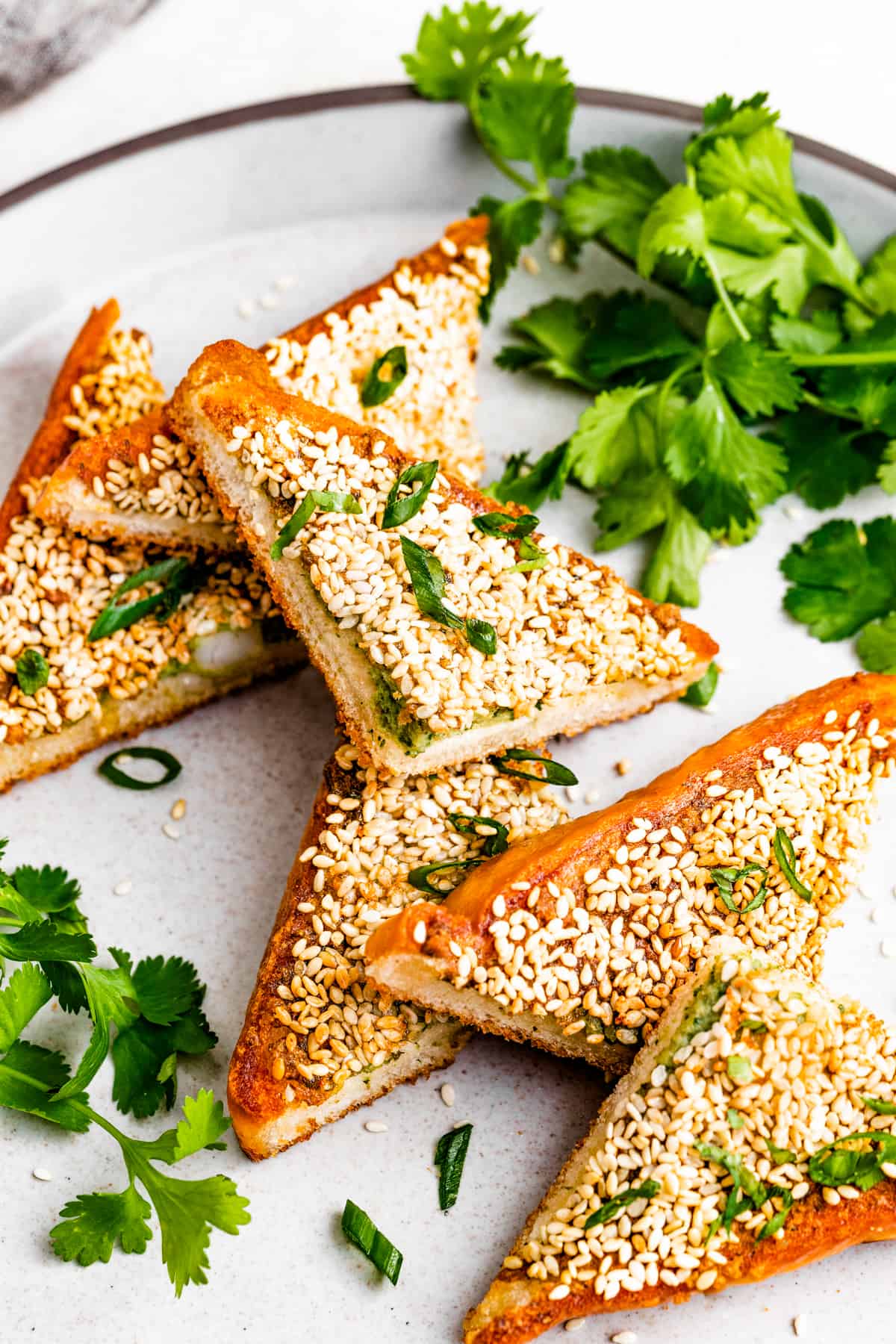 Overhead photo of shrimp toast triangles garnished with cilantro and scallions.