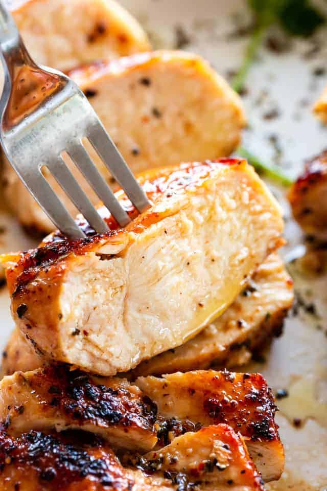A fork spearing a piece of juicy chicken breast